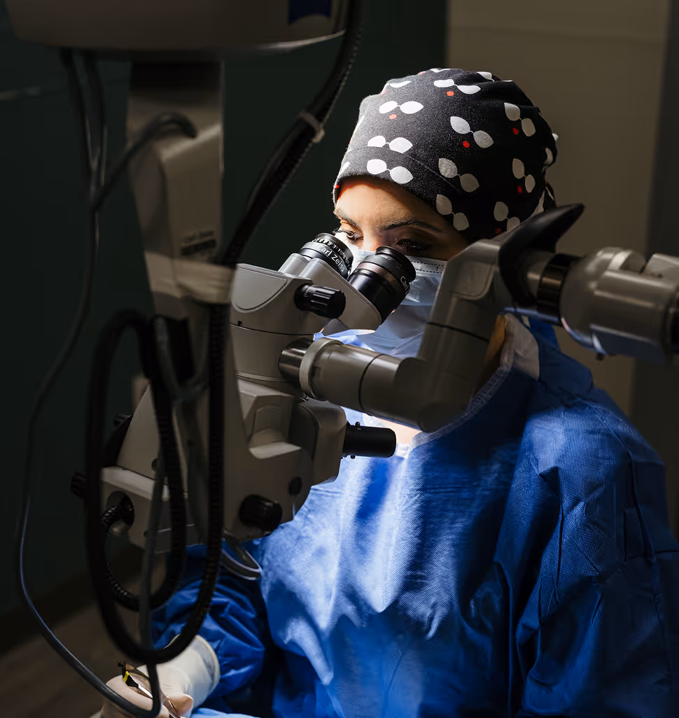 Dr. Minella performing surgery at a microscope