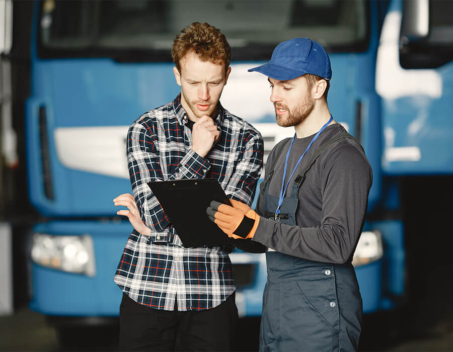 Logistics worker discussing delivery checklist with client in front of freight truck