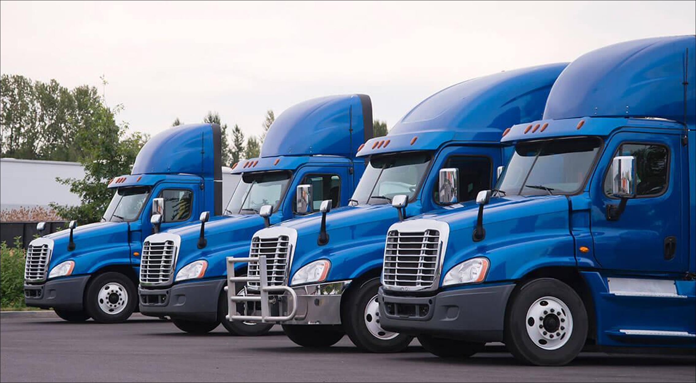 Fleet of blue semi-trucks parked in a row representing power-only trucking services