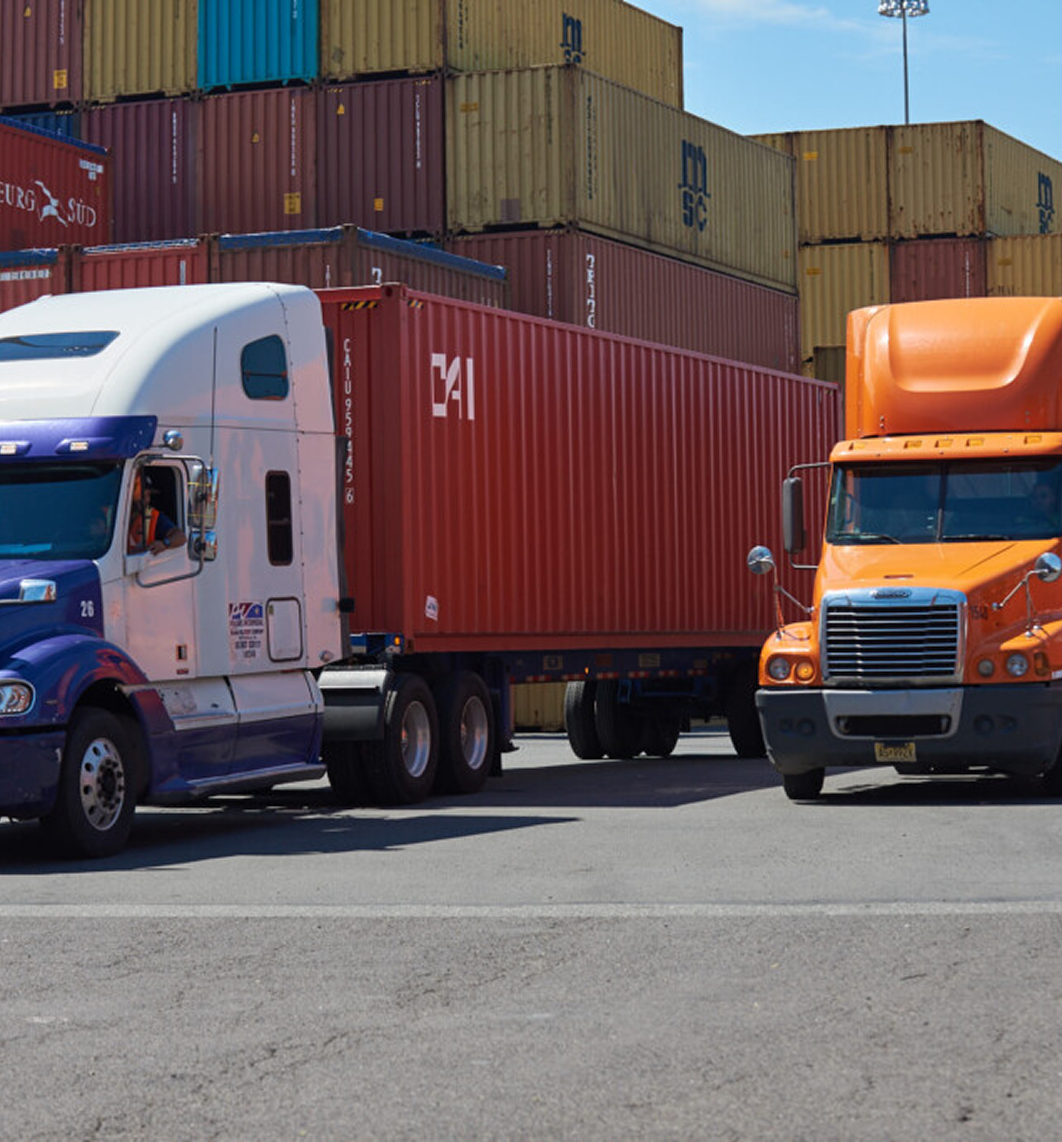 Semi-trucks transporting intermodal containers at shipping terminal for freight delivery