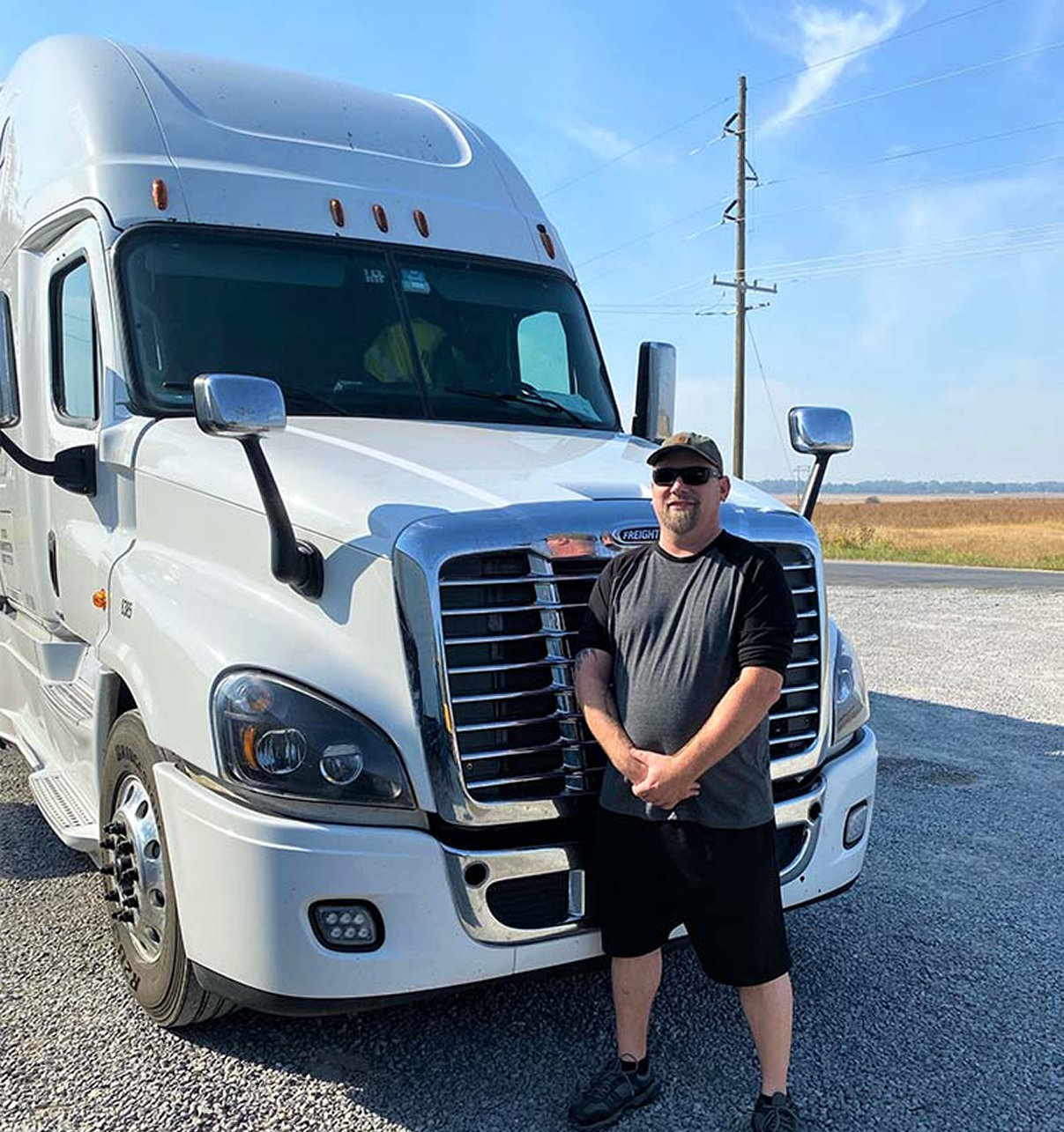 Truck driver standing in front of white semi-truck representing dedicated and nationwide freight services
