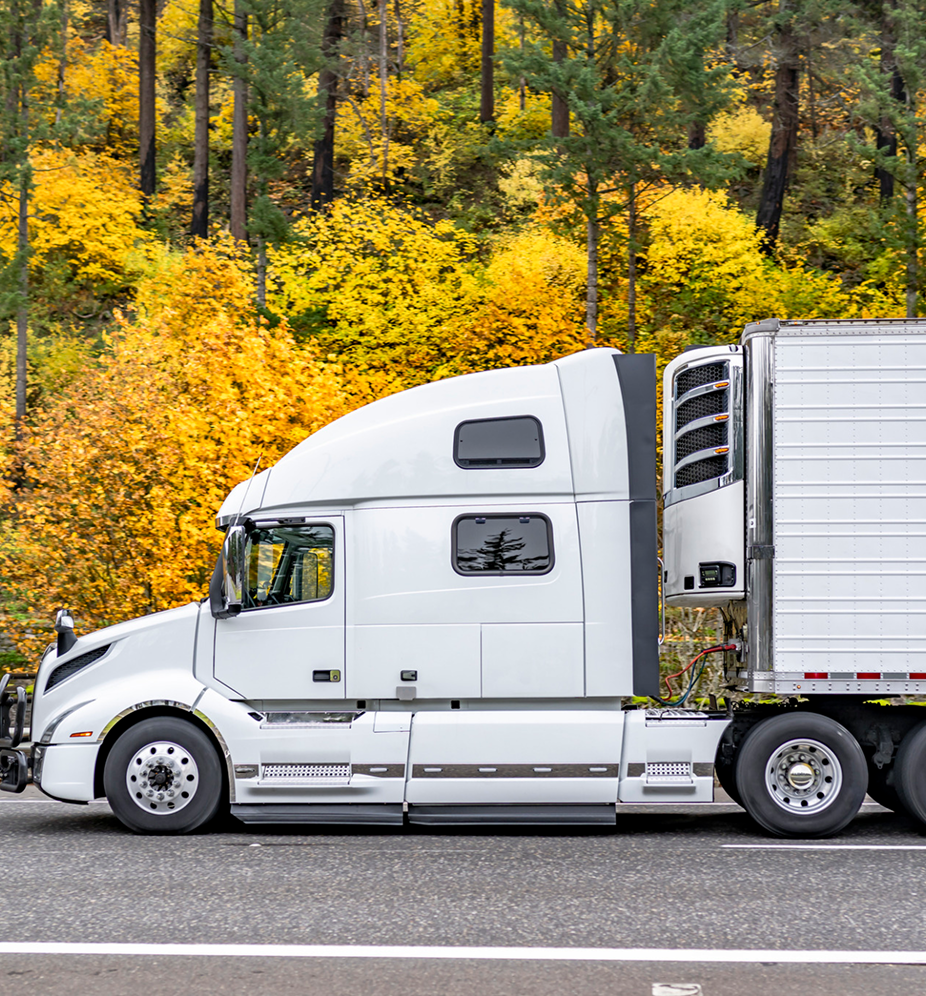 White semi-truck hauling refrigerated trailer on highway for temperature-controlled freight transport