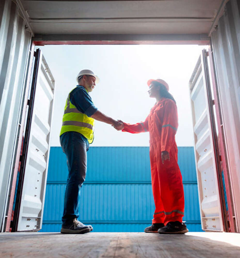 Logistics workers shaking hands inside shipping container representing freight partnership