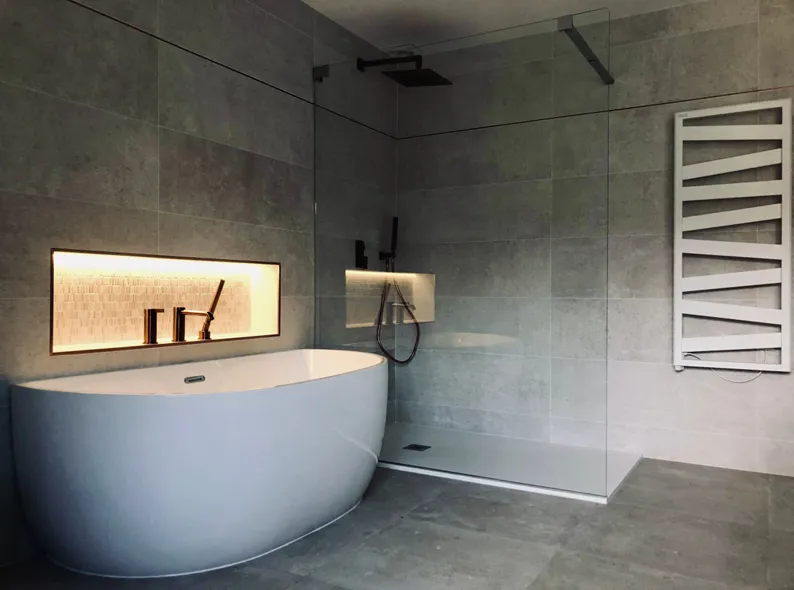 Salle de bain en pierre grise avec baignoire îlot et douche à l'italienne
