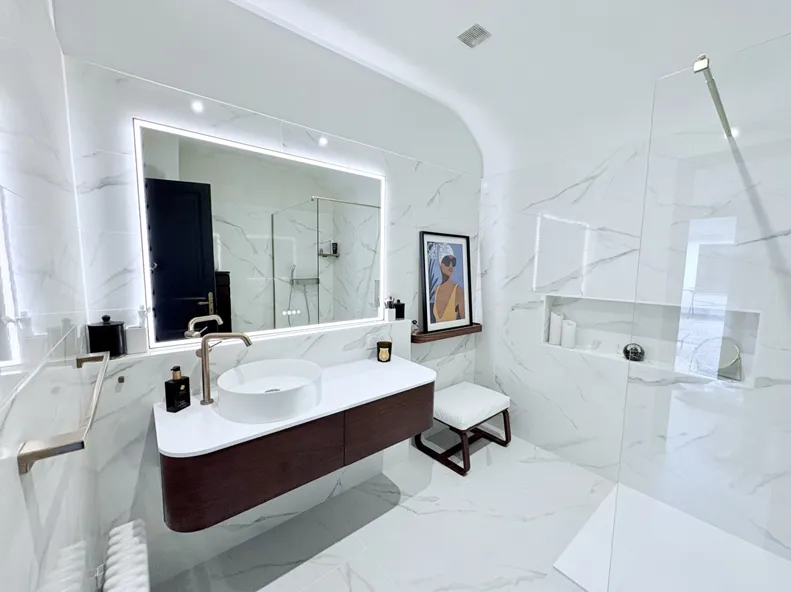 Salle de bain en marbre blanc avec meuble suspendu et douche vitrée