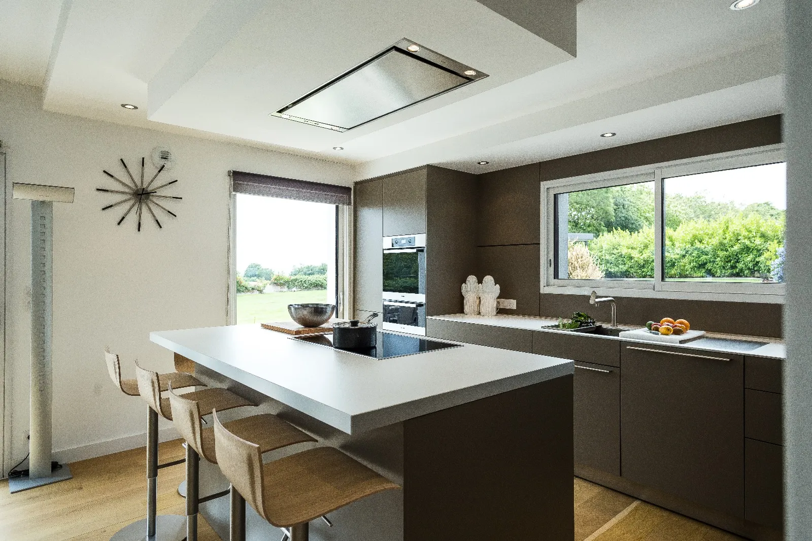Cuisine avec îlot central, hotte design et vue sur jardin
