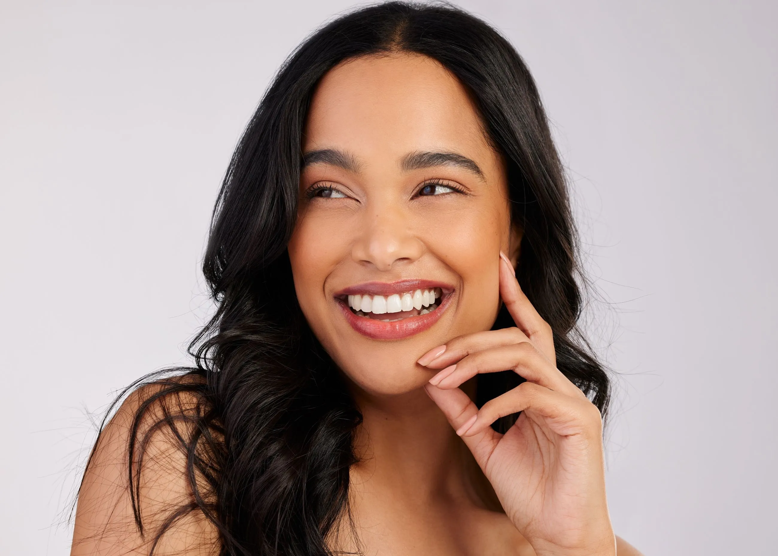 A woman smiling and holding her hand to her face.