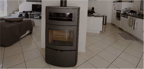 Modern black wood-burning stove positioned against a wall, with a living room on the left and a kitchen on the right.