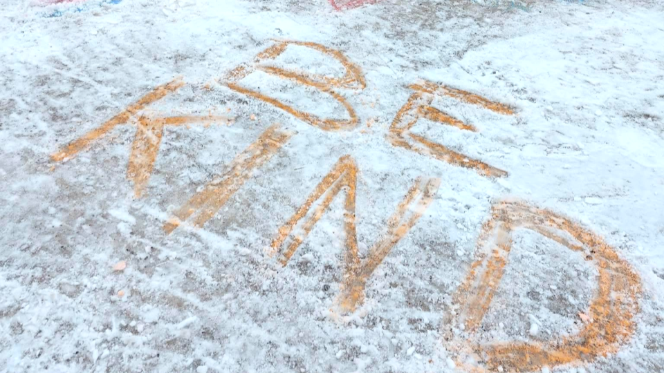 The words be kind are written in snow. 