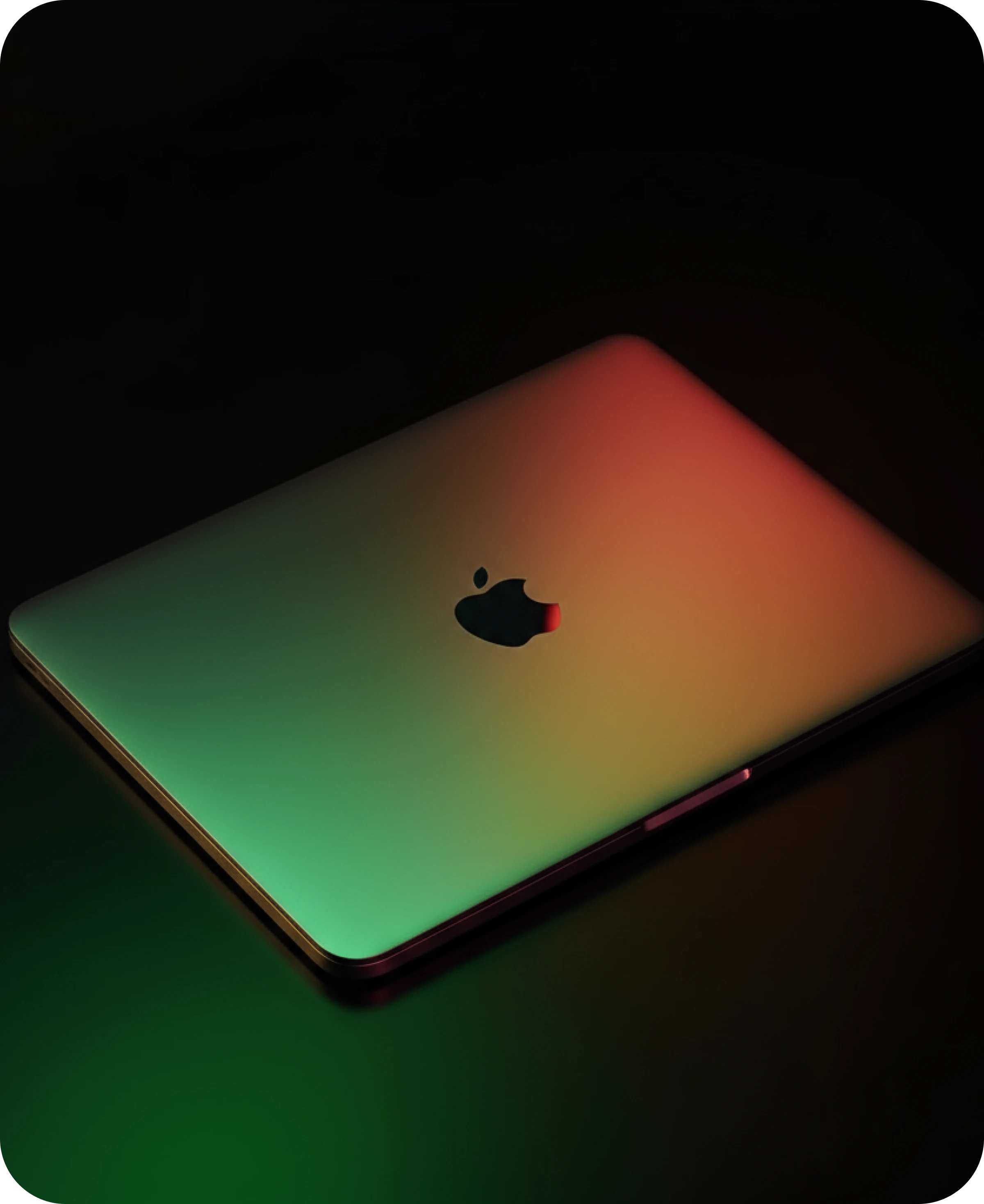 Closed MacBook laptop with gradient red and green light reflection on the lid, symbolizing modern technology and creative design.