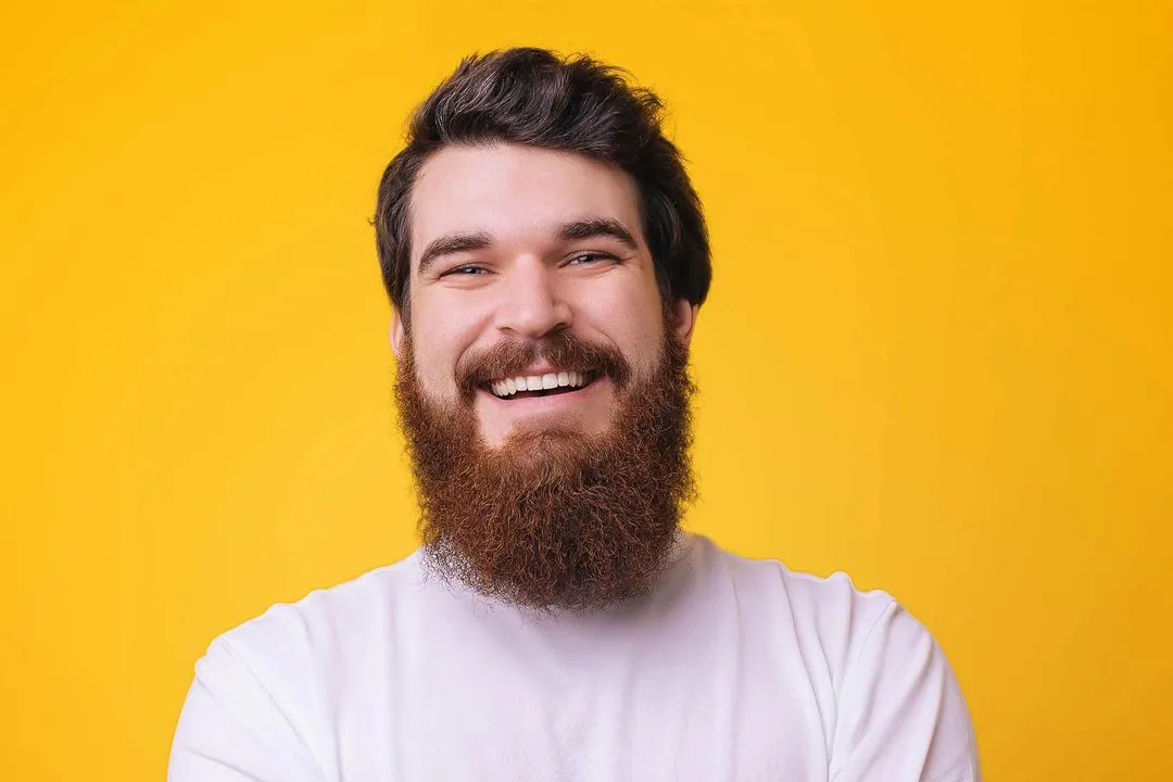 A man with a beard smiling and wearing a white shirt.