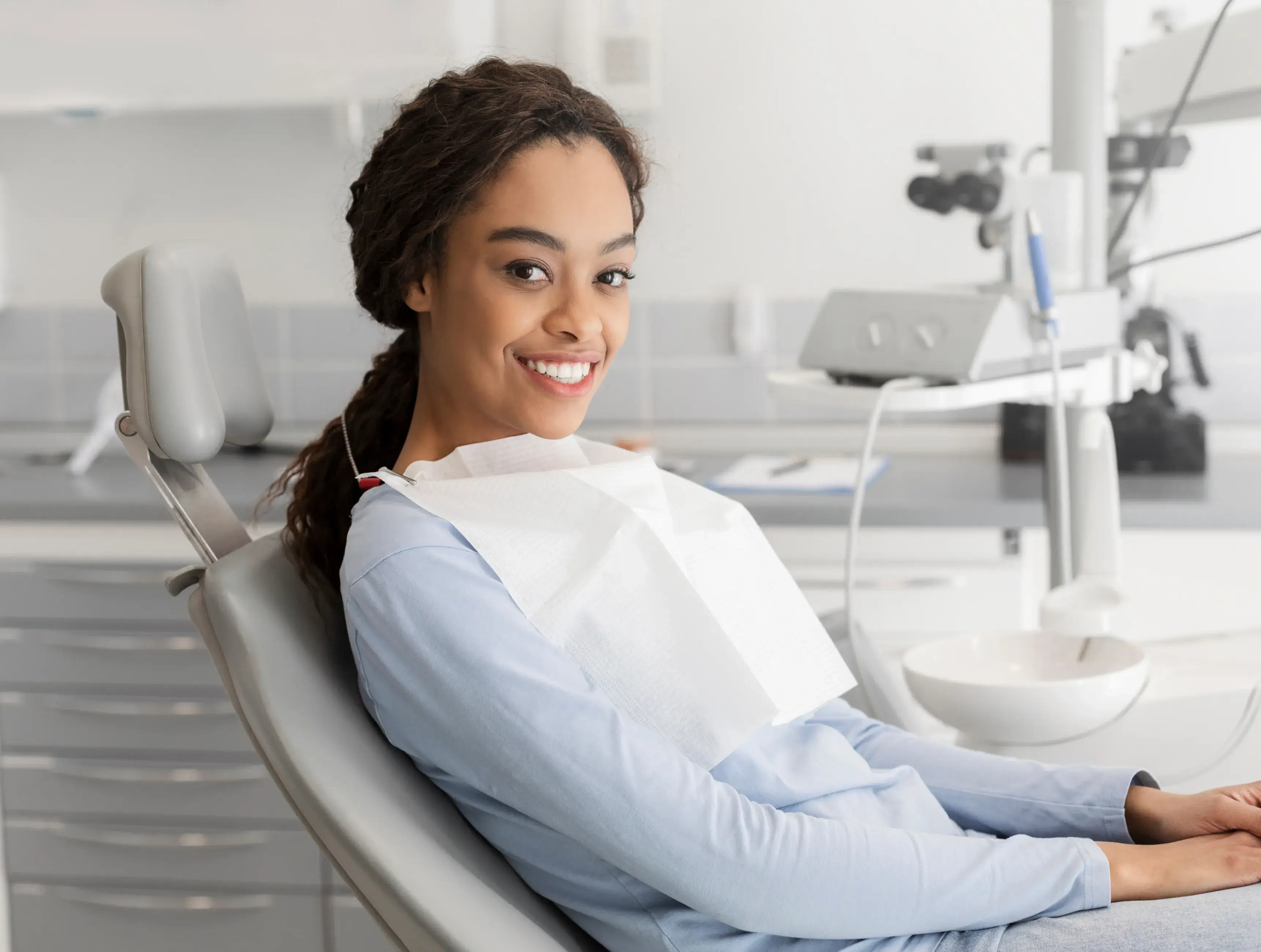 A woman sitting in a dental chair smiling.