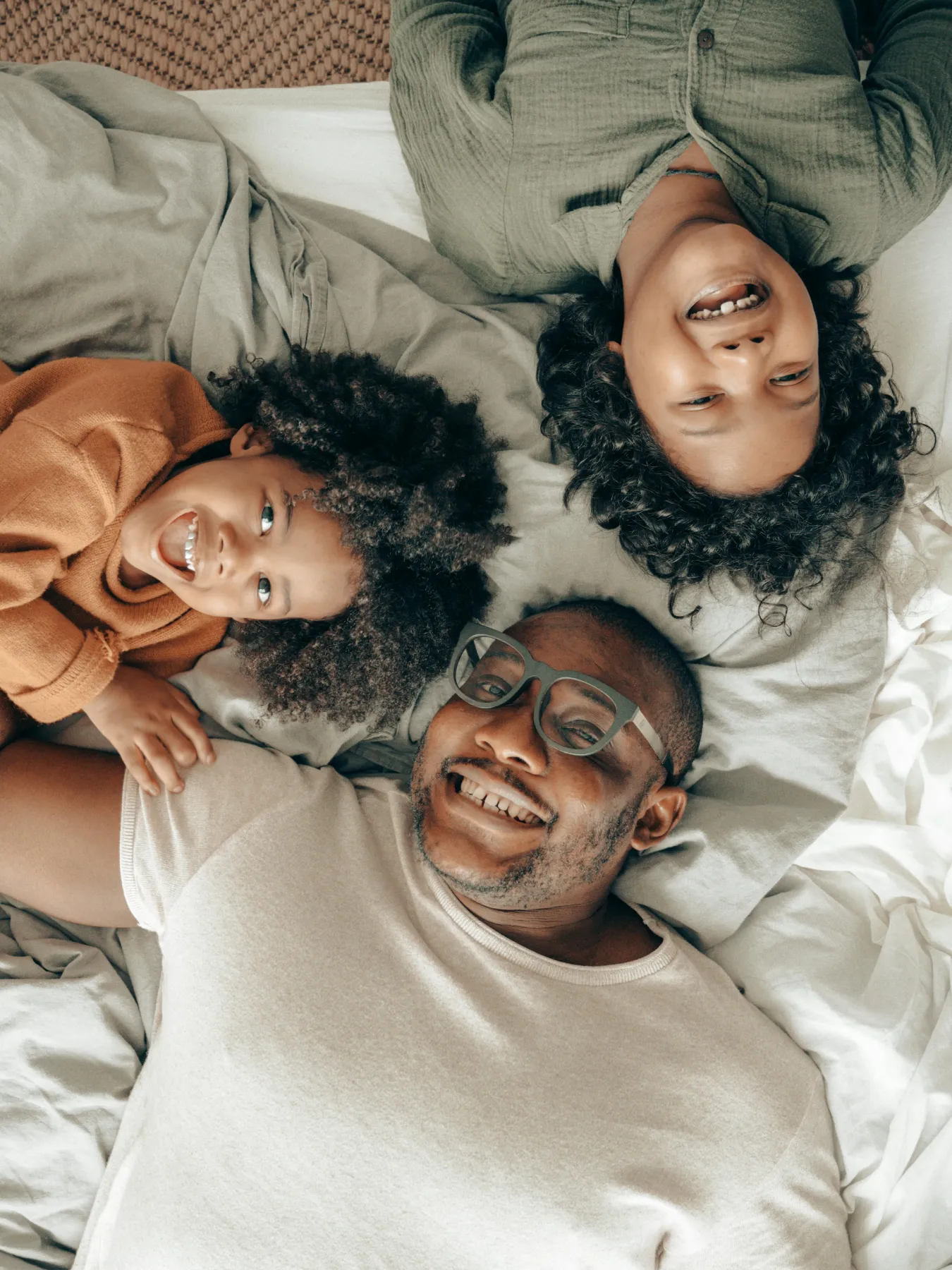 A man and two children laying on a bed.
