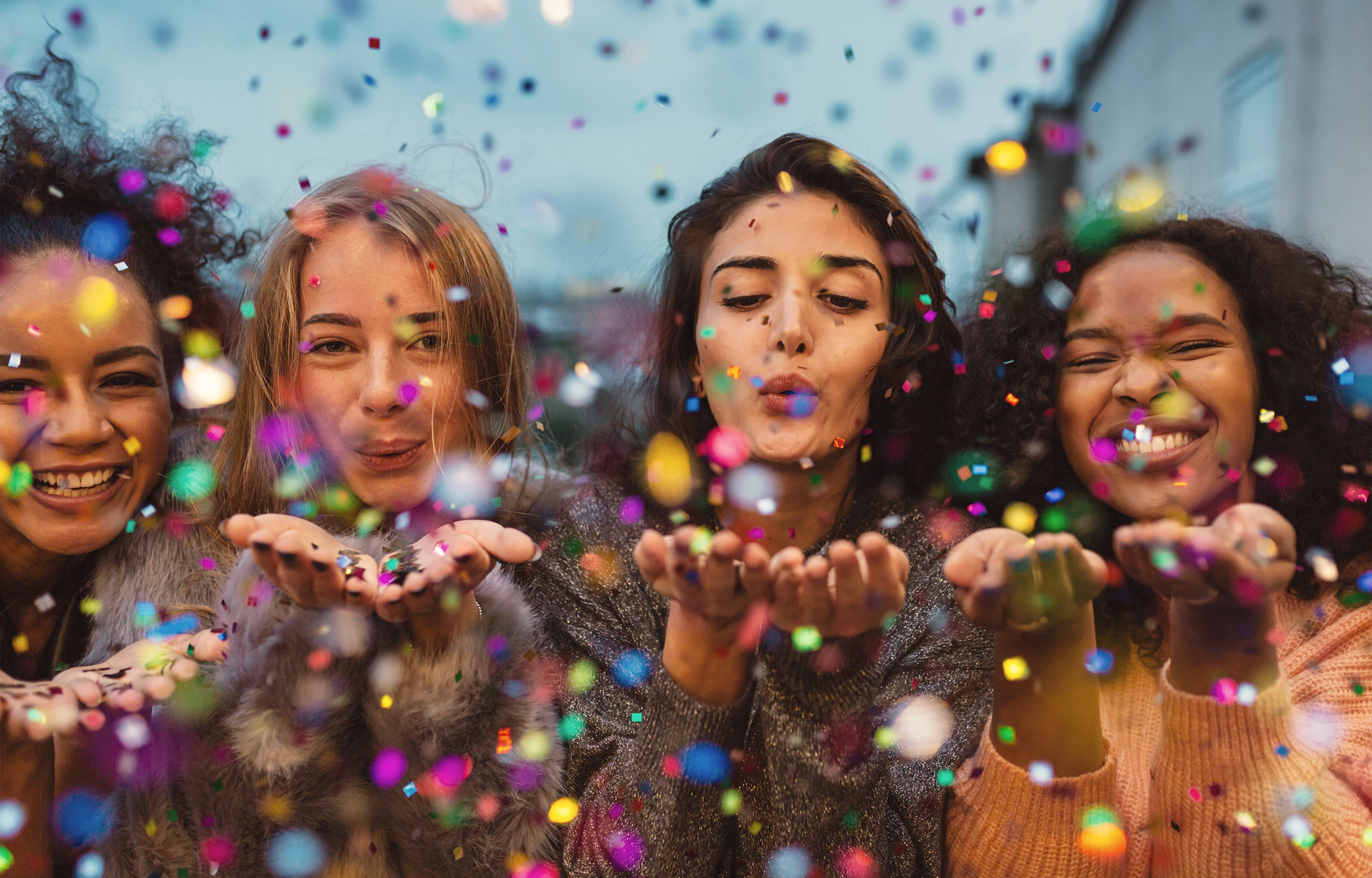 girls blowing confetti at camera