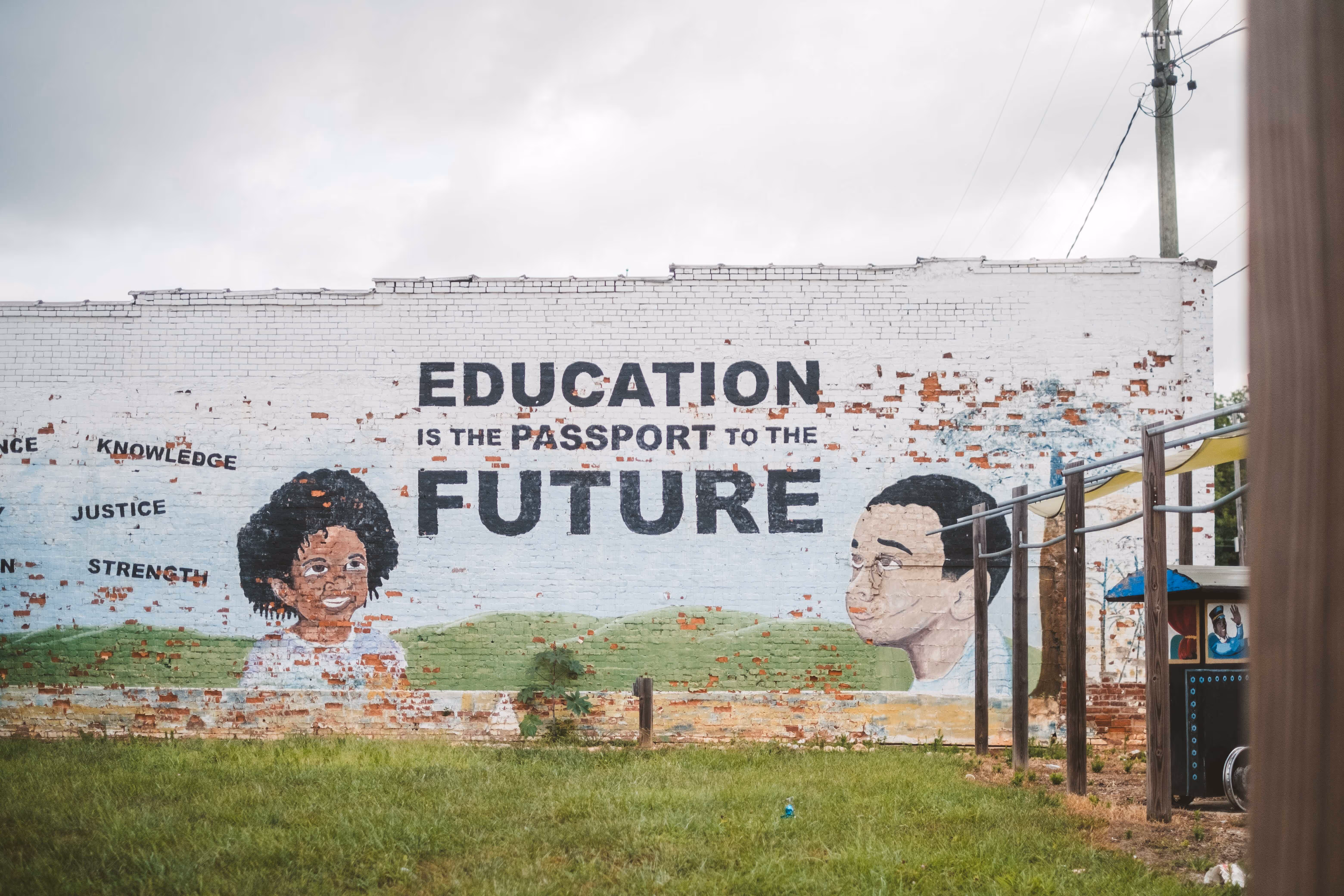 A mural on a brick wall that reads "Education is the passport to the future"