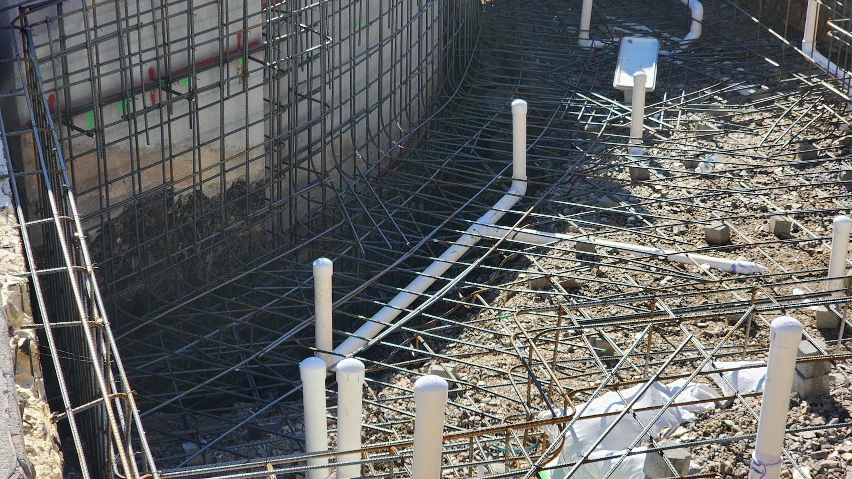 Hillside pool construction progress showing rebar cage installation and structural engineering on steep Scottsdale slope