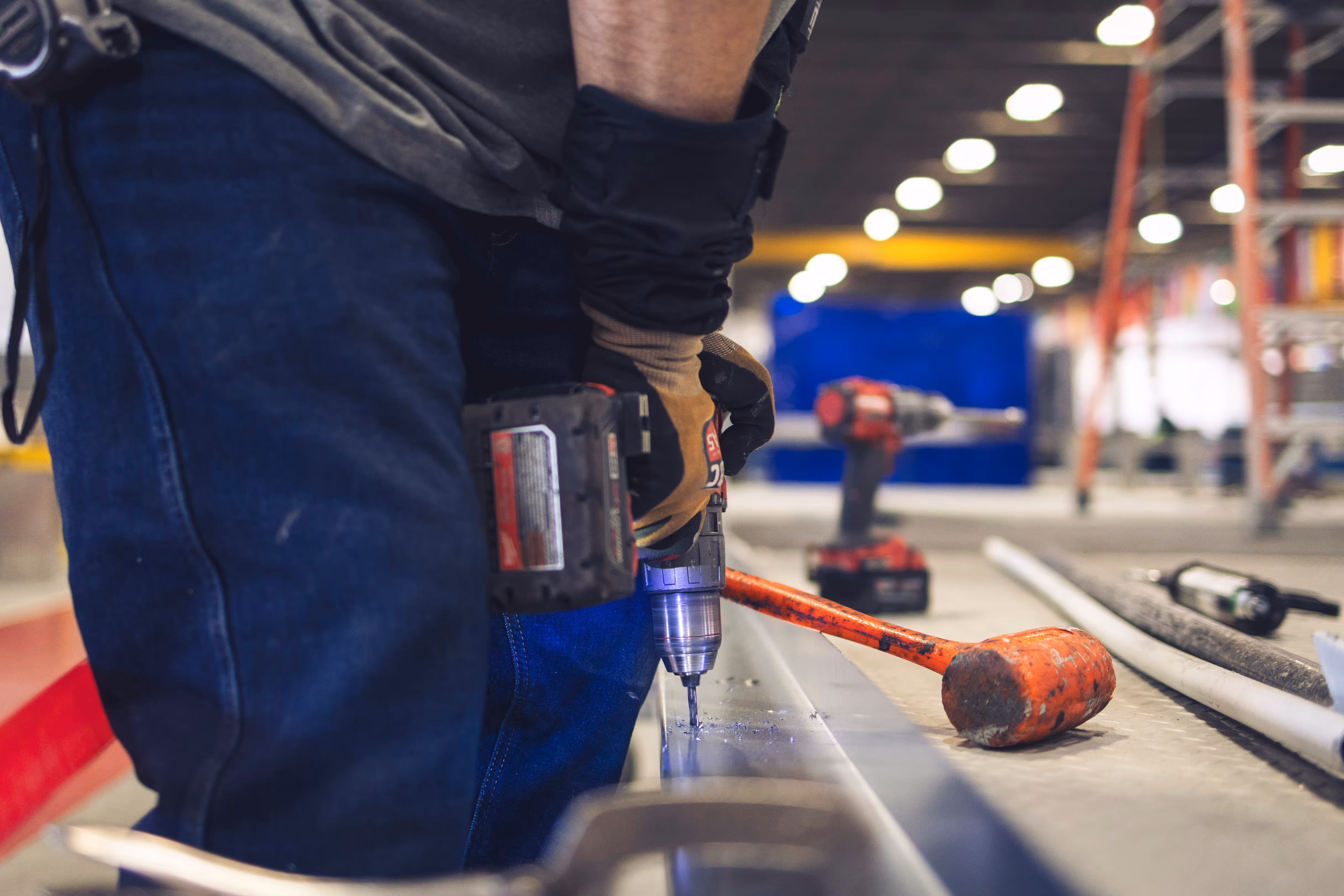 Worker drilling metal surface with power tool in industrial workshop