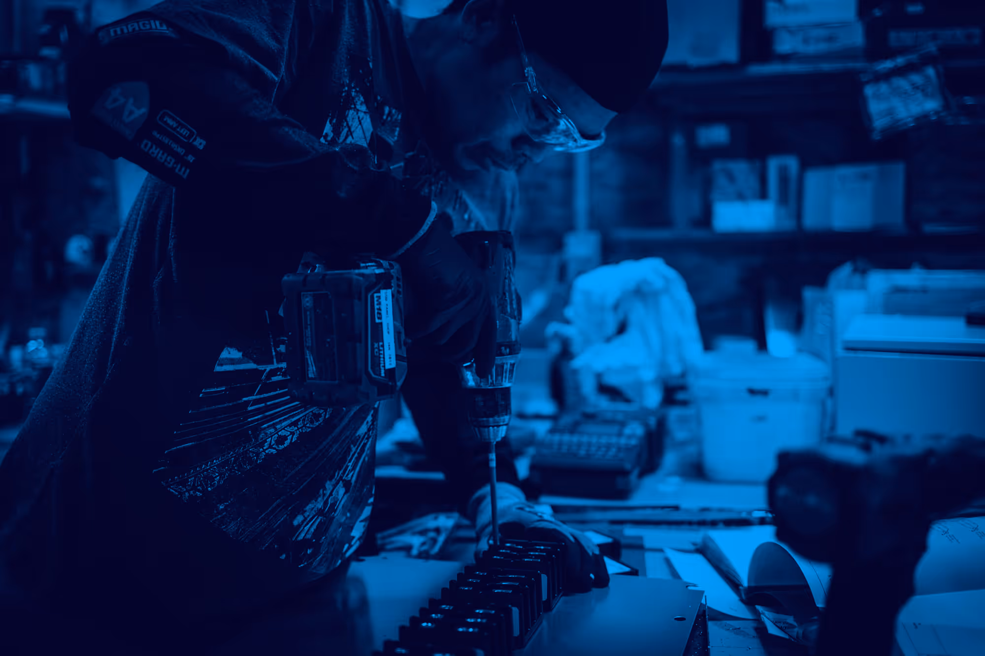 Blue-tinted industrial workspace with drilling machine and scattered equipment