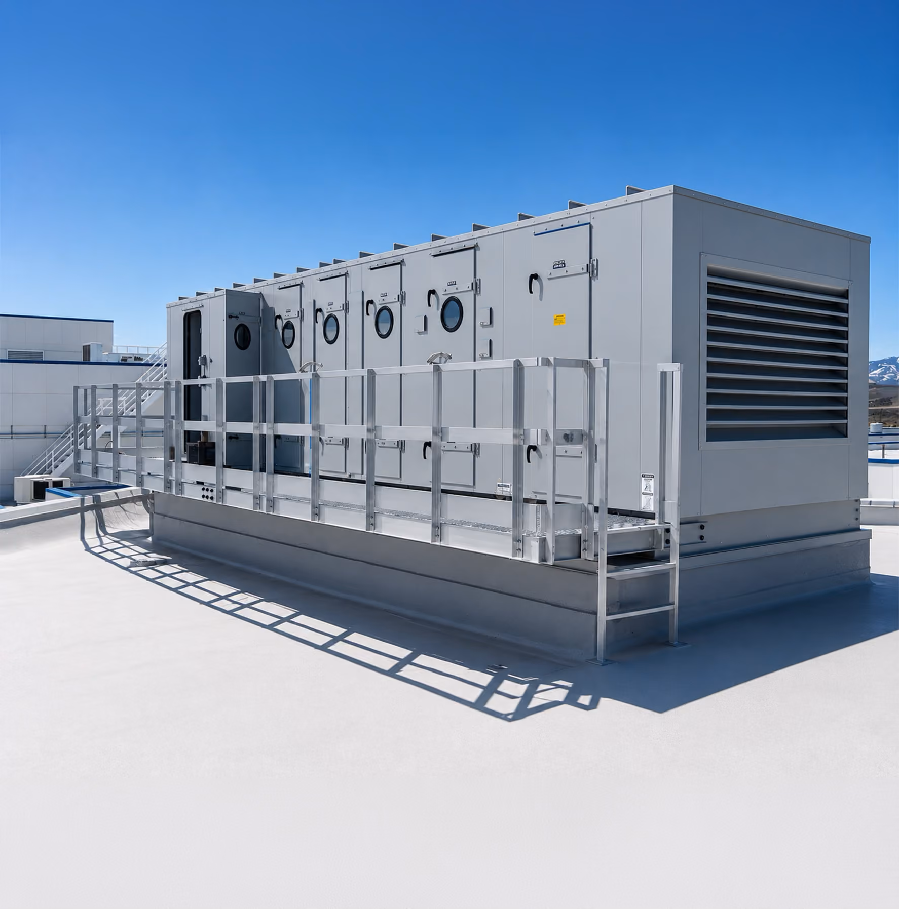 Large rooftop industrial air handling unit with access doors and safety railings under clear blue sky.