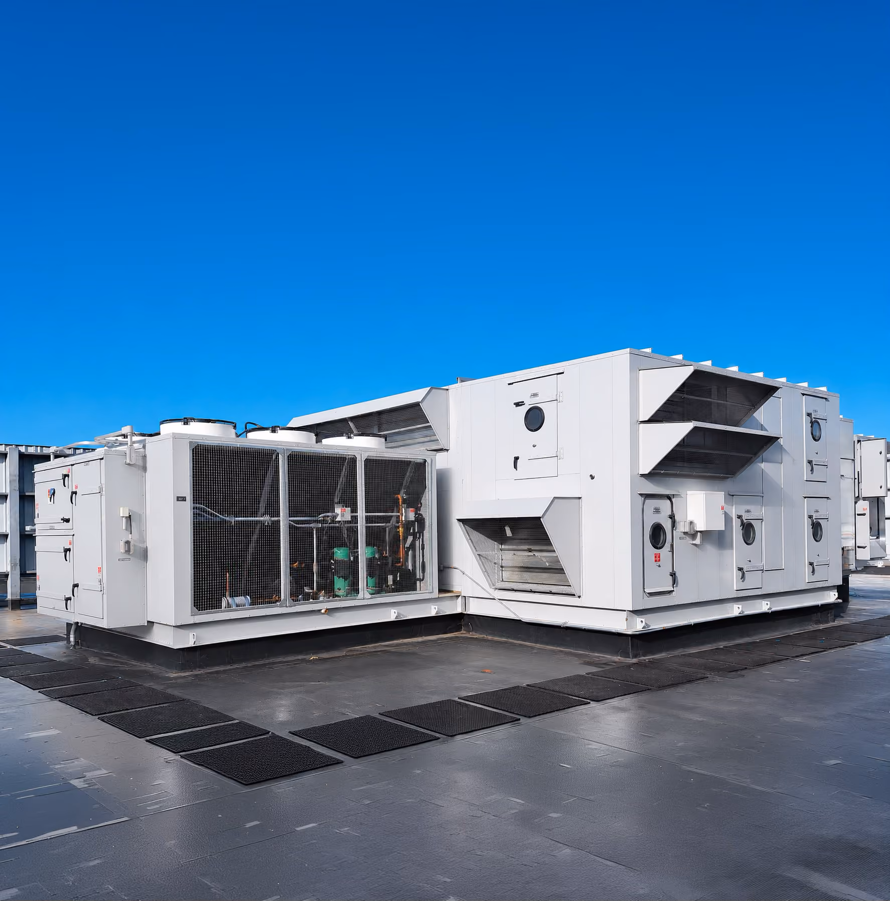 Large commercial HVAC units installed on a flat rooftop under a clear blue sky.