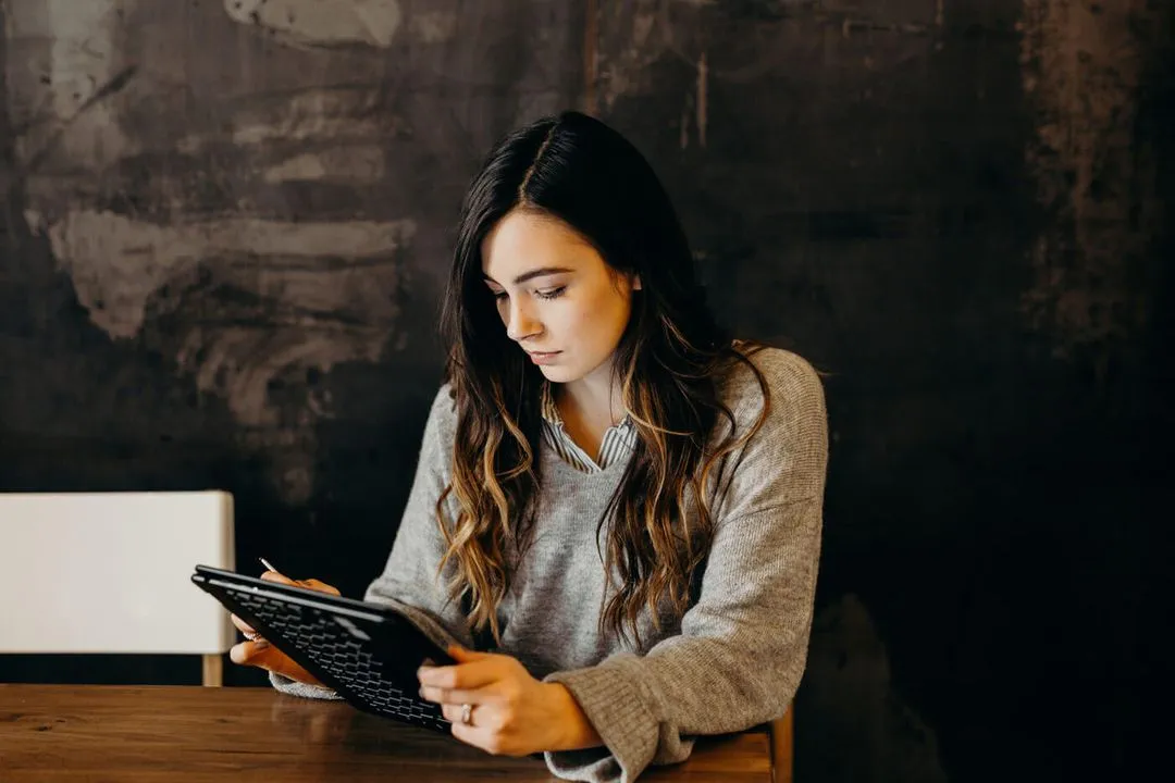 Professional young woman, working on a tablet at a table.
