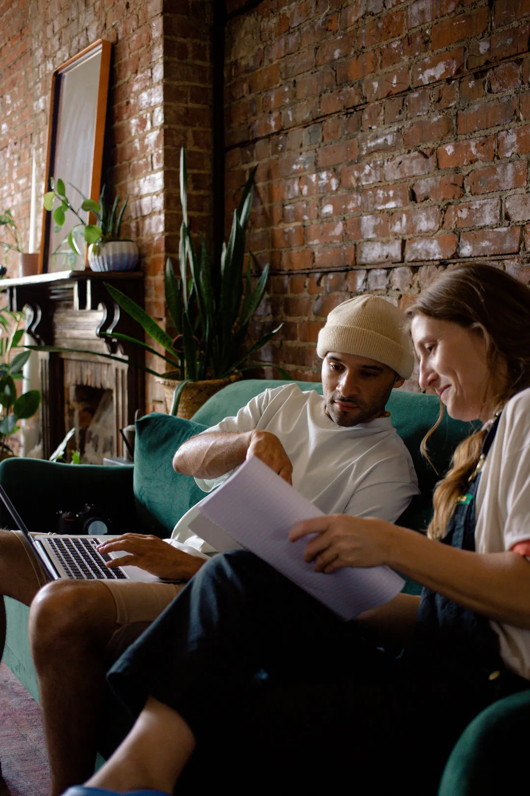 Two people working collaboratively on a sofa together.