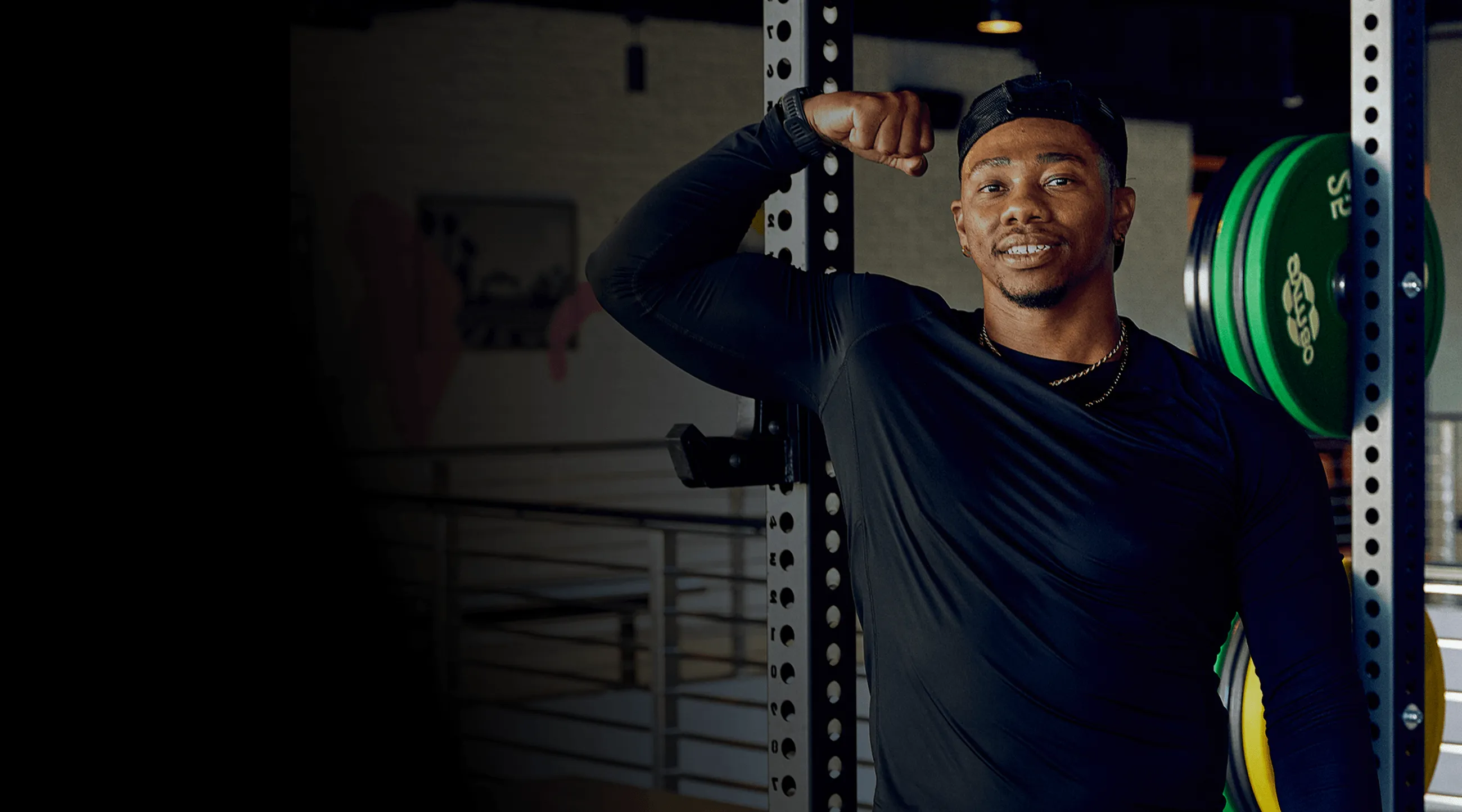 A man standing next to a barbell in a gym.