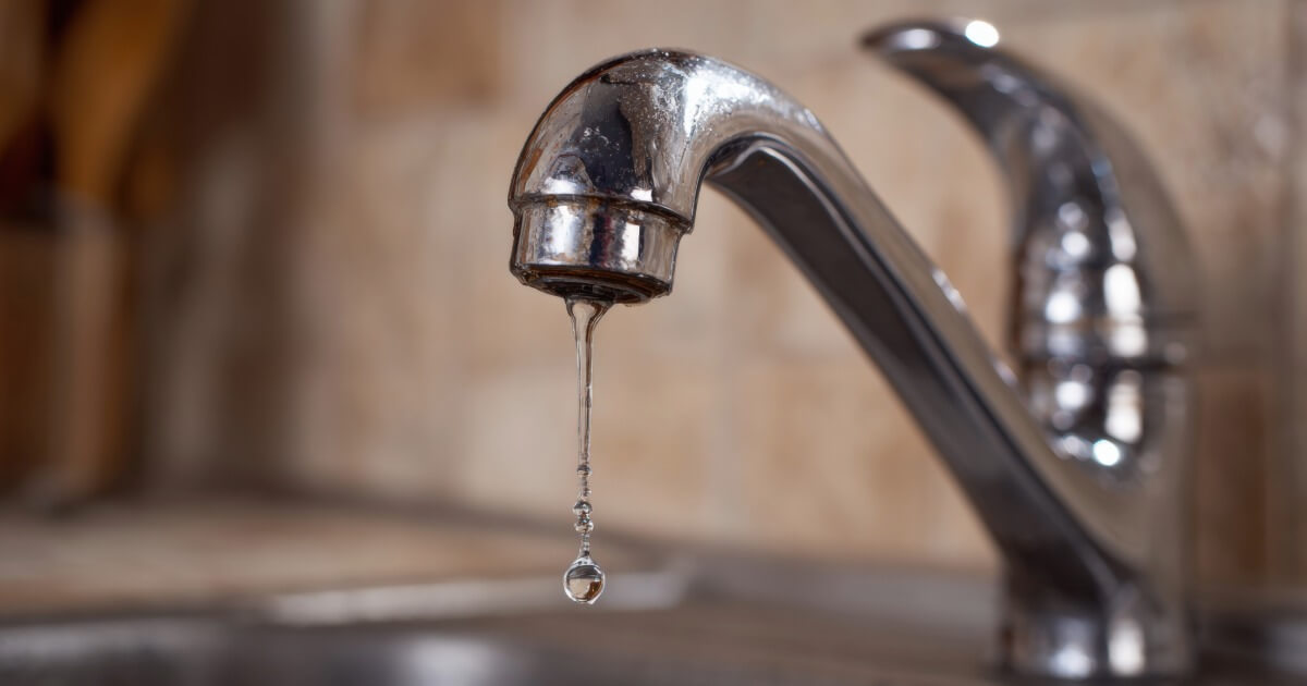 Close-up of a kitchen faucet with a single water droplet, highlighting water conservation and plumbing.