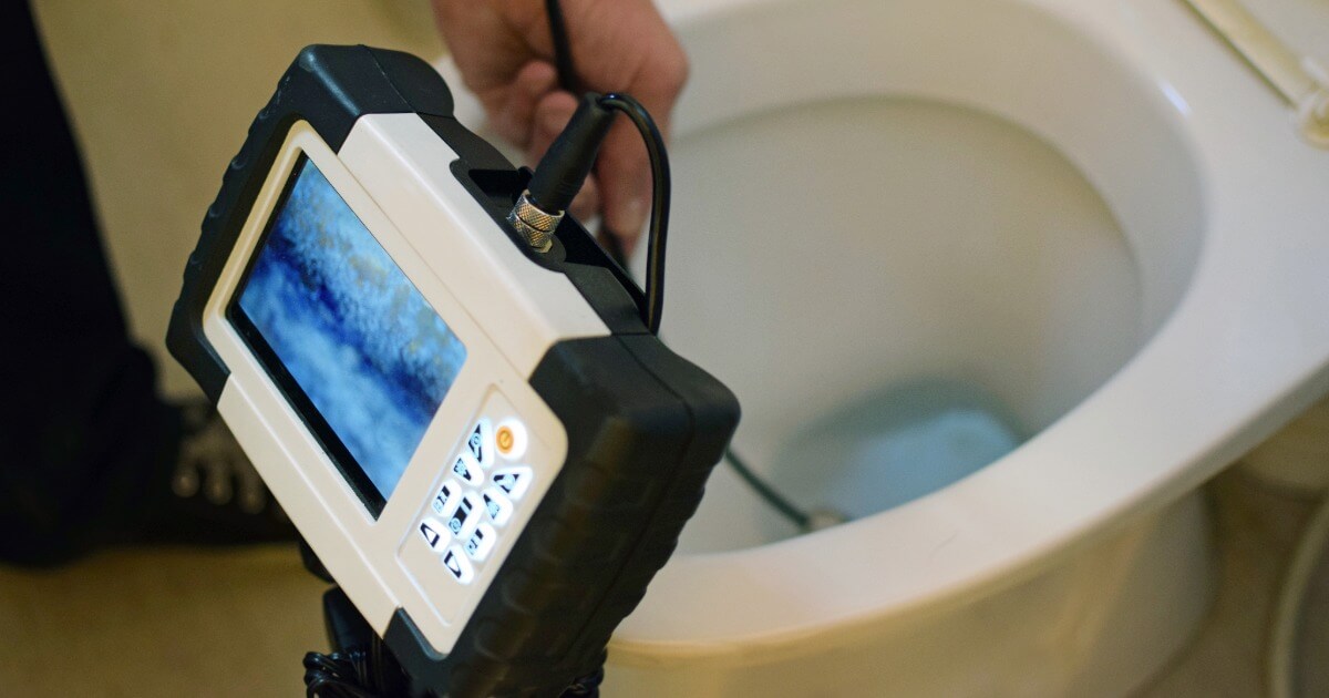 Inspection camera examining a toilet drain for plumbing maintenance or blockage detection.