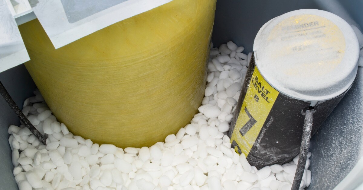 Inside view of a water softener tank with white salt pellets.