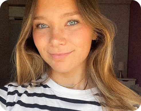 Portrait d'une jeune femme aux cheveux longs blonds et yeux clairs portant un t-shirt rayé noir et blanc, souriant légèrement.