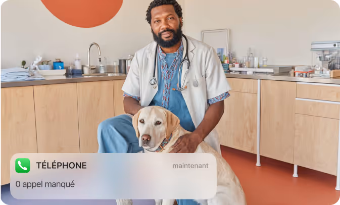 Un vétérinaire assis avec un chien Labrador beige dans une clinique vétérinaire moderne.