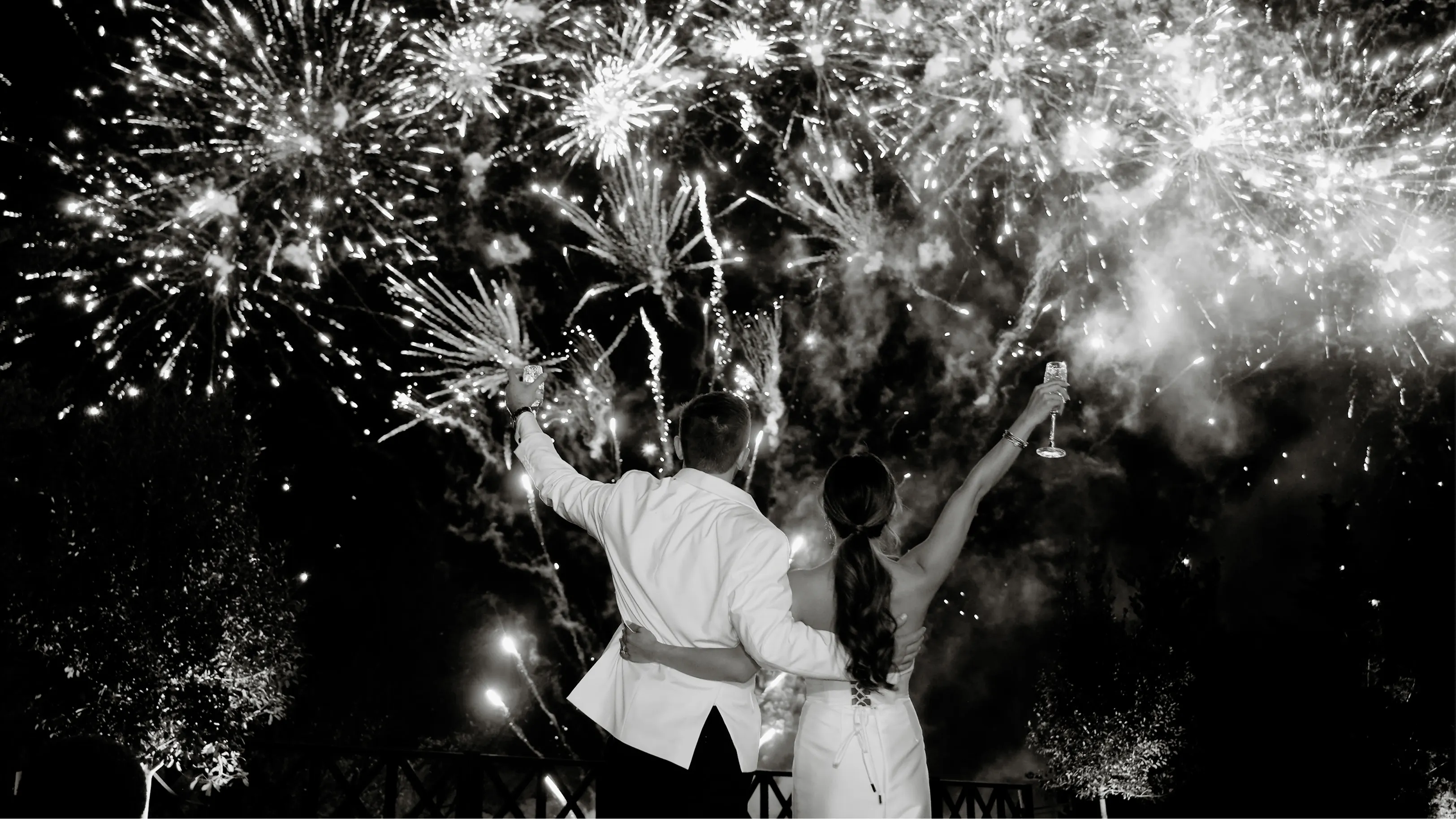 Bride and groom standing close on a decorative staircase with floral mural background, smiling at each other.