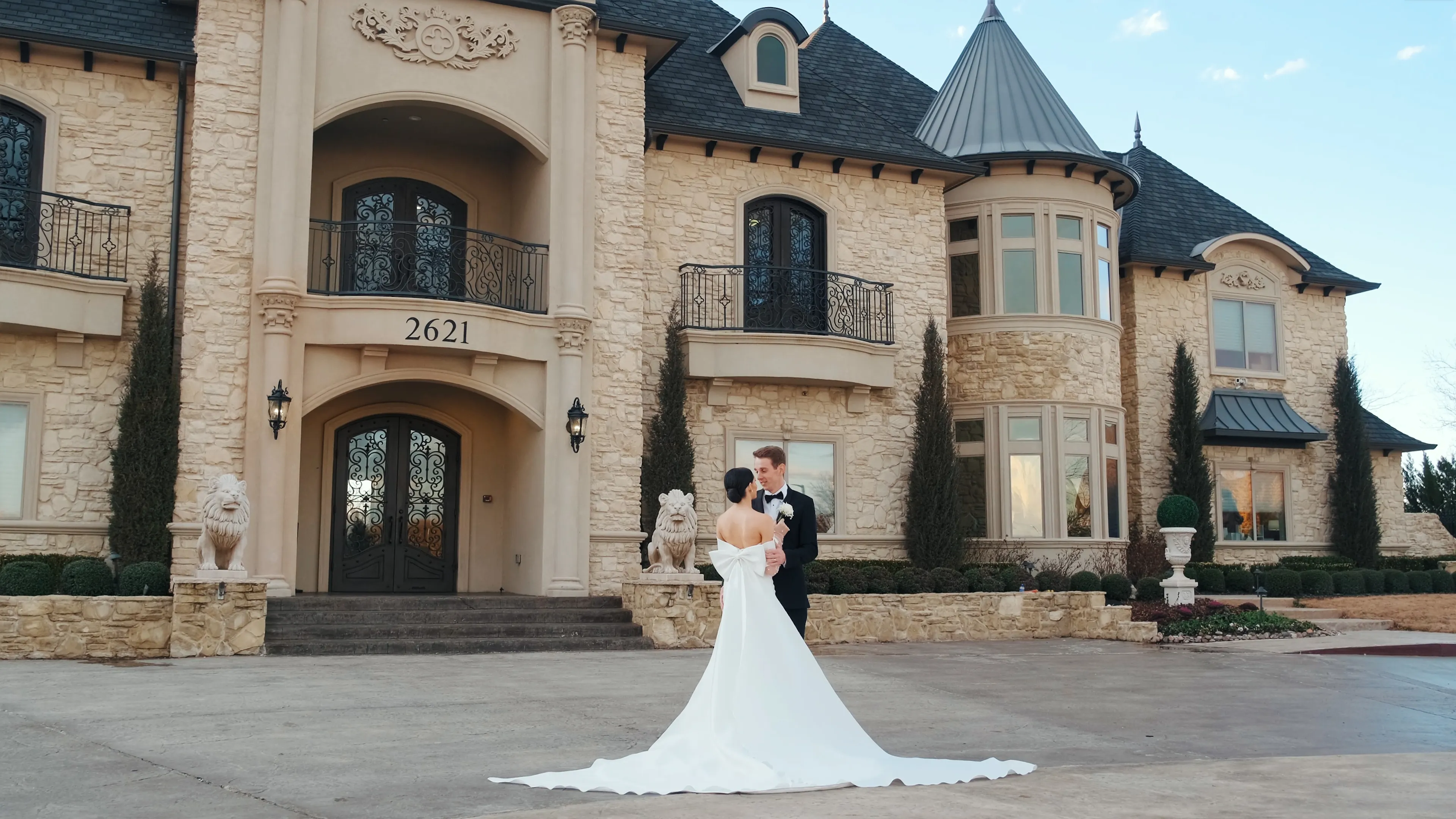 Bride and groom standing close on a decorative staircase with floral mural background, smiling at each other.