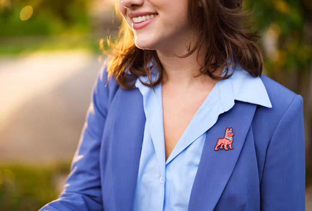 Smiling woman wearing a blue blazer with a red dog-shaped pin on the lapel.
