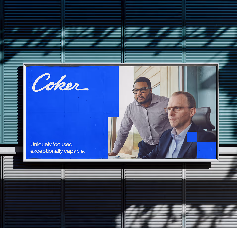 Billboard with blue and white design featuring two men in business attire, one standing and one seated, with the text 'Coker' and 'Uniquely focused, exceptionally capable.'