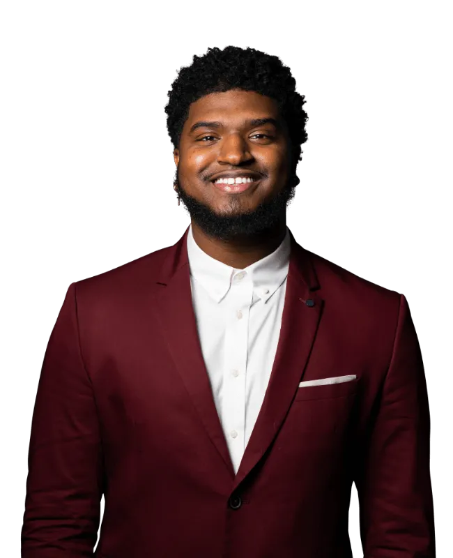 Justin wearing a maroon suit jacket and white shirt against a black background.