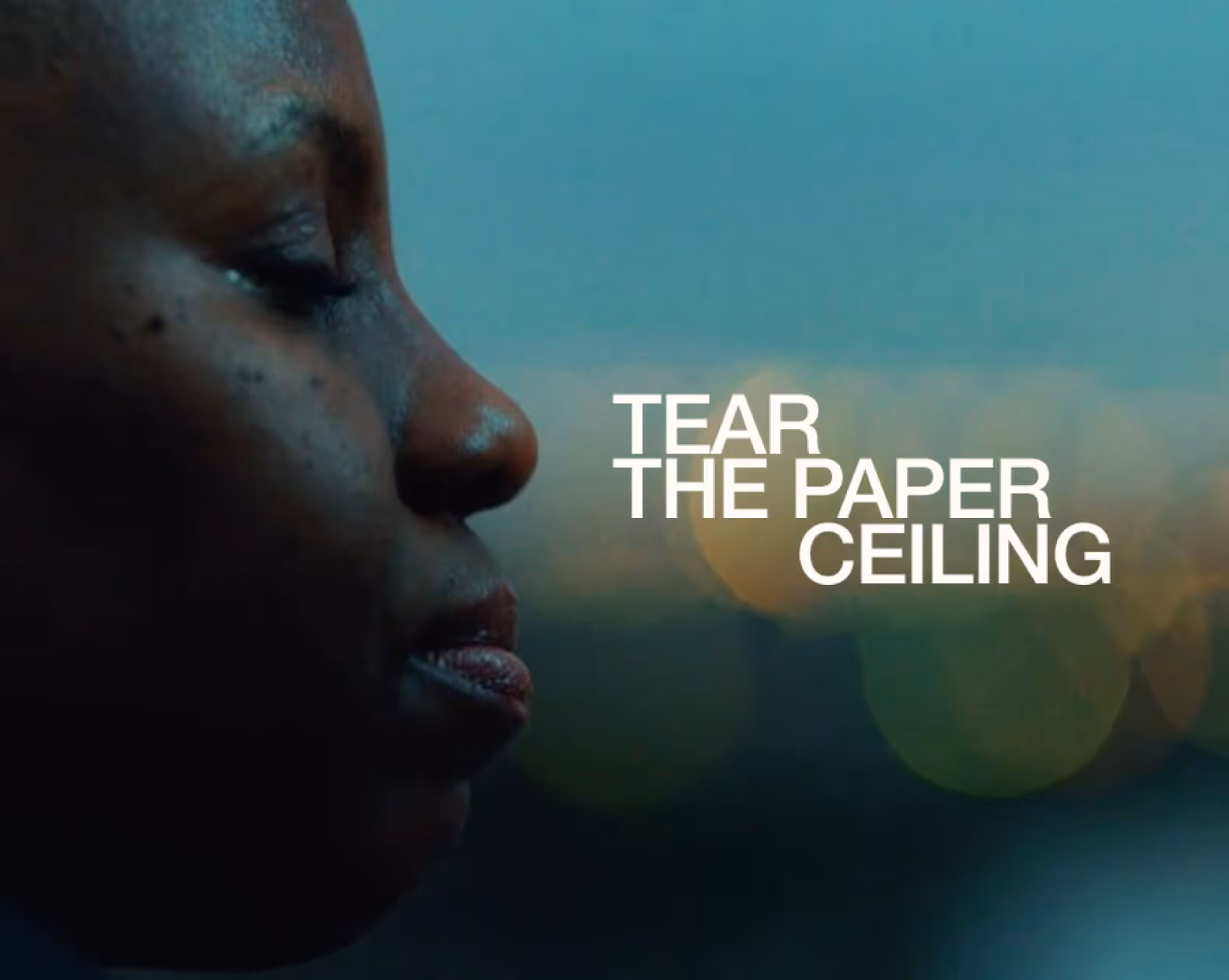 Close-up profile of a person's face with eyes closed and text 'Tear the paper ceiling' against a blurred blue and green background.