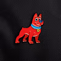Red cartoon dog pin with blue collar and yellow tag on black textured fabric.