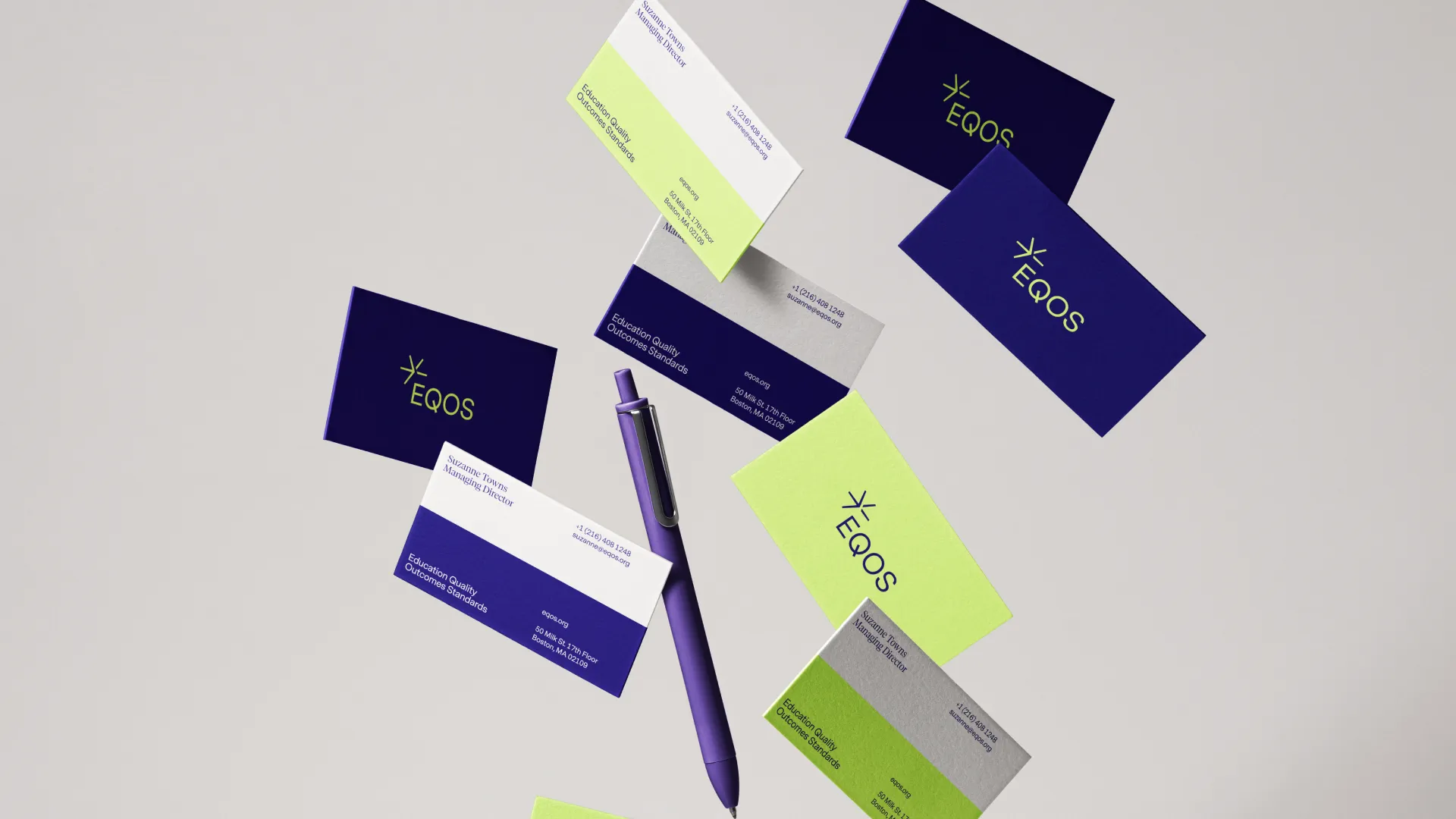 Purple pen surrounded by dark blue and lime green EQOS business cards with contact details for Suzanne Towns, Managing Director.