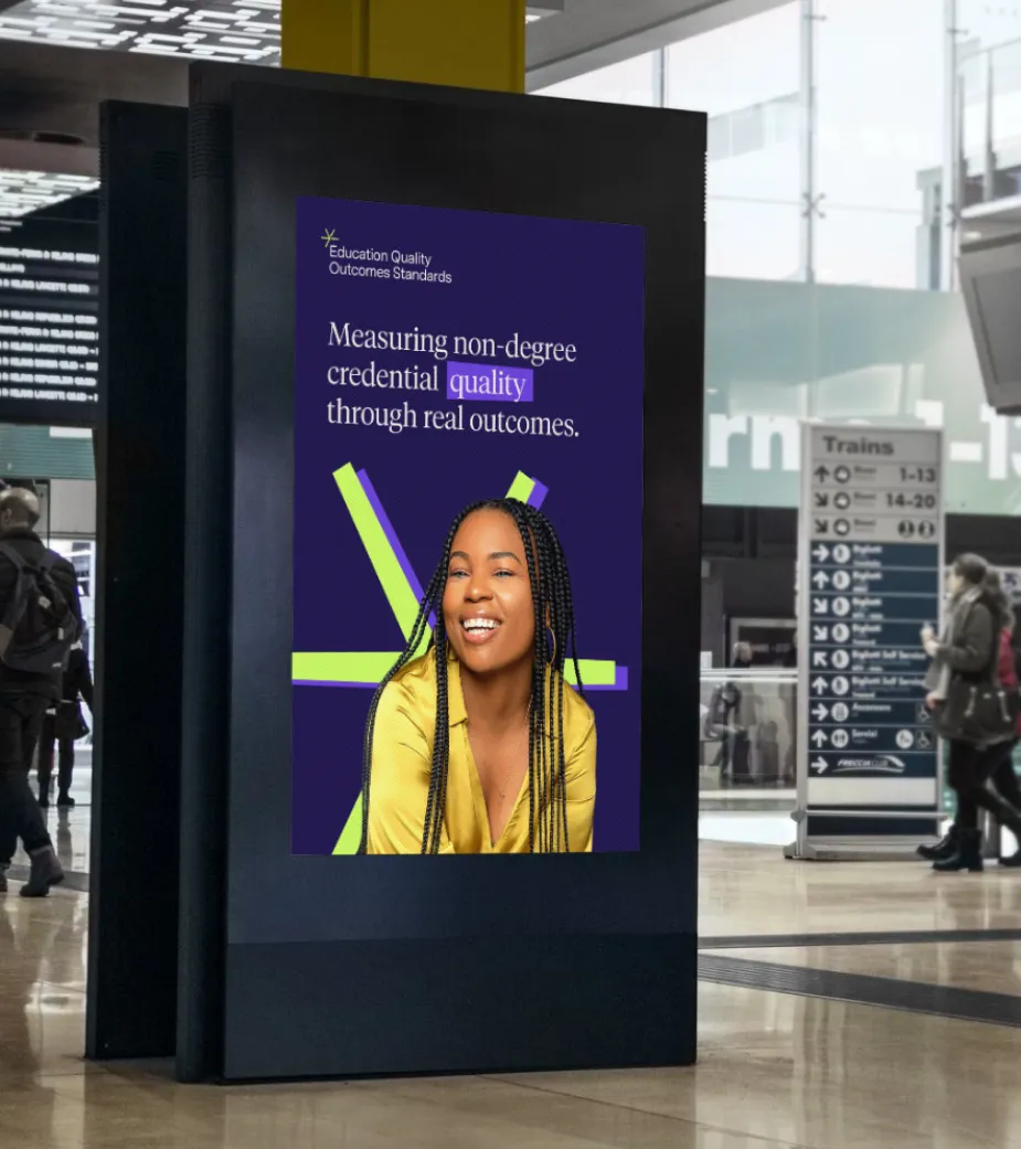 Digital advertisement in a train station showing a smiling woman with braided hair and text about measuring non-degree credential quality through real outcomes.