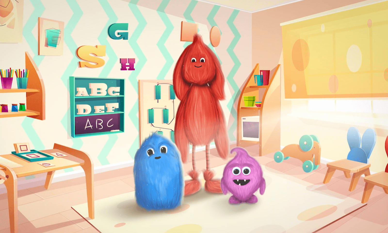 Three colorful furry monster characters in a bright, playful classroom with alphabet letters and toys.