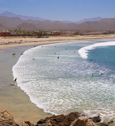 Playa del Pacífico cerca de Todos Santos con personas practicando actividades acuáticas