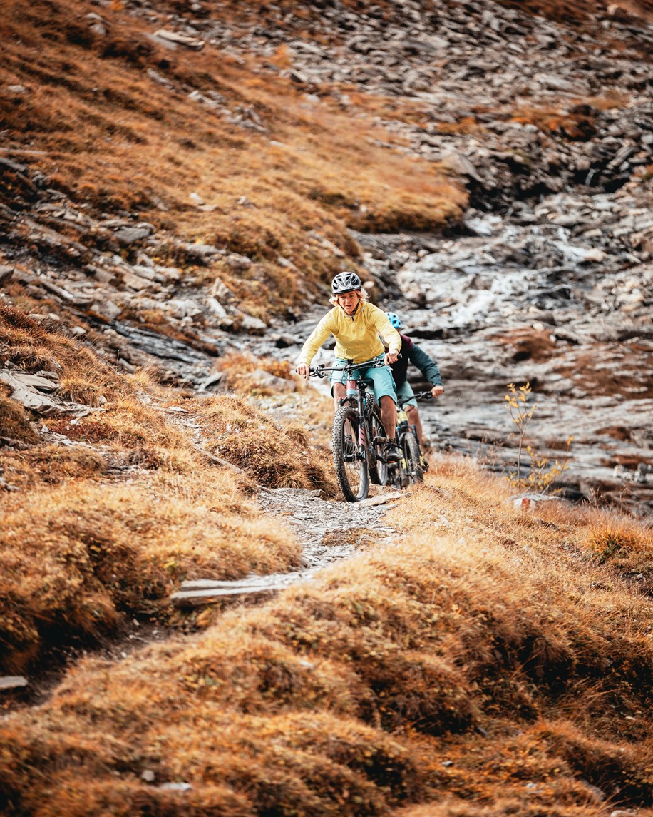Two riders going down a technical trail