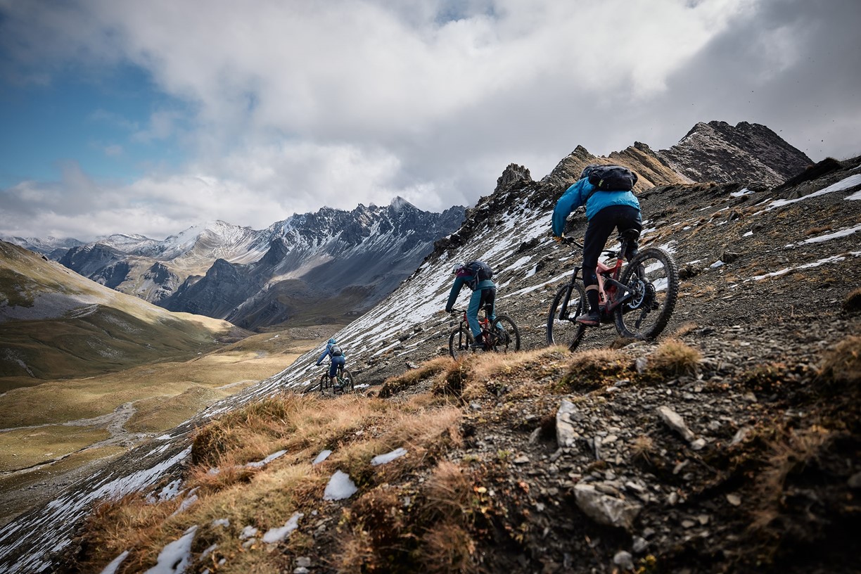 Three riders on a steep, alpine descent in the Grisons Alps