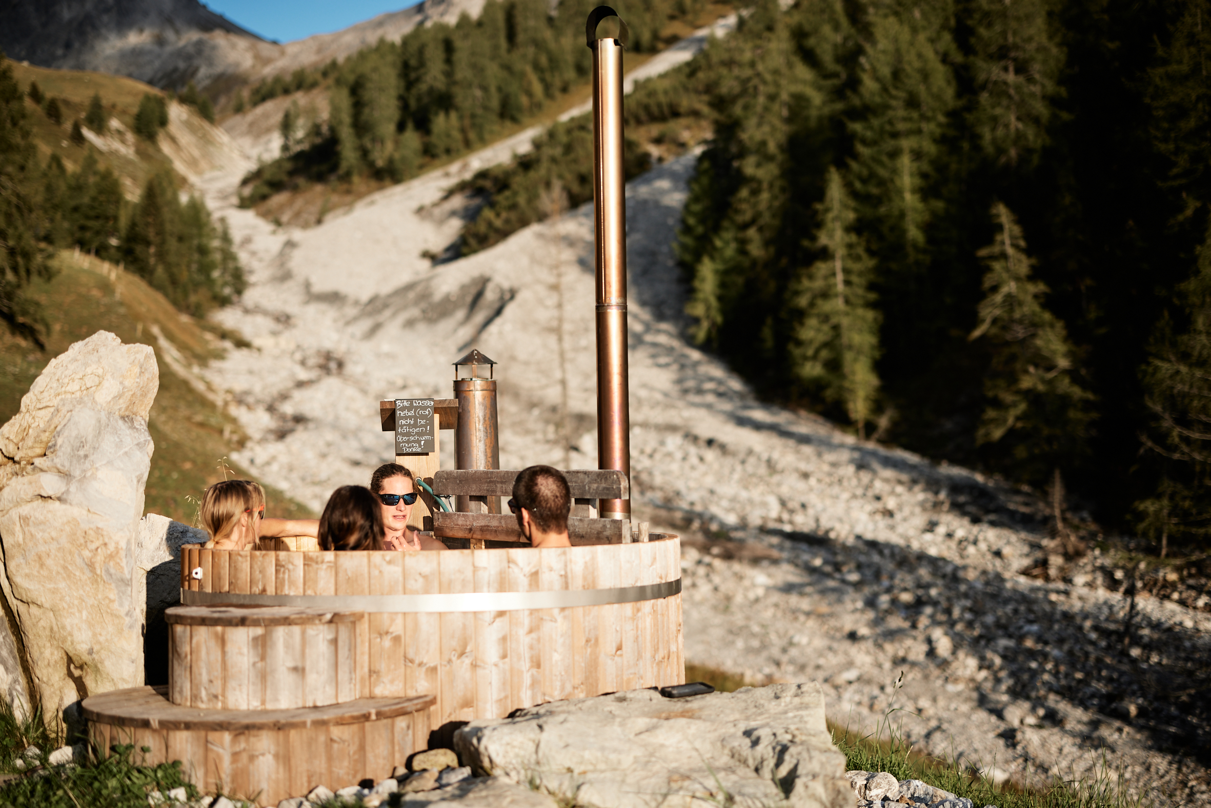 A group enjoying a dip in an outdoor wooden hot tub.