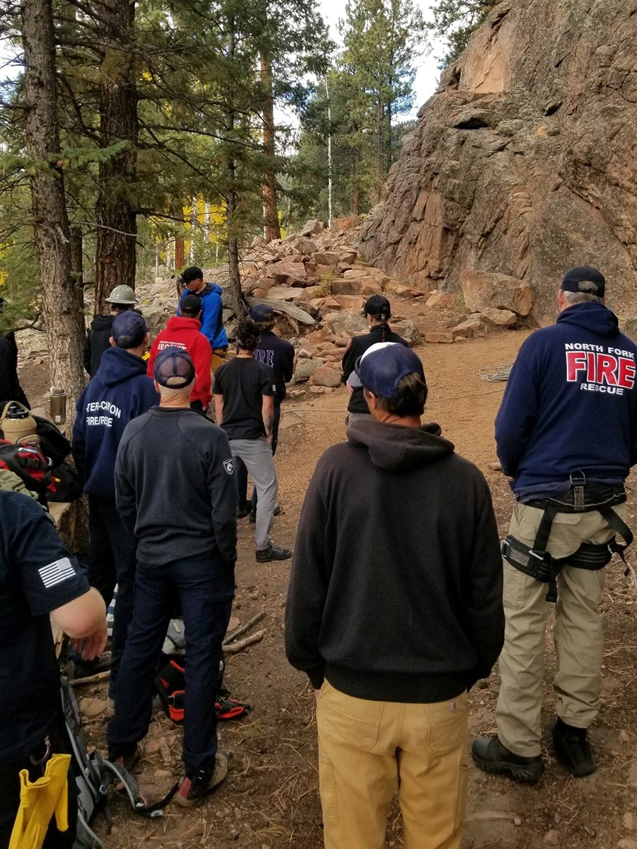 Firefighters gathered near a rock formation during a mountain rescue training exercise.