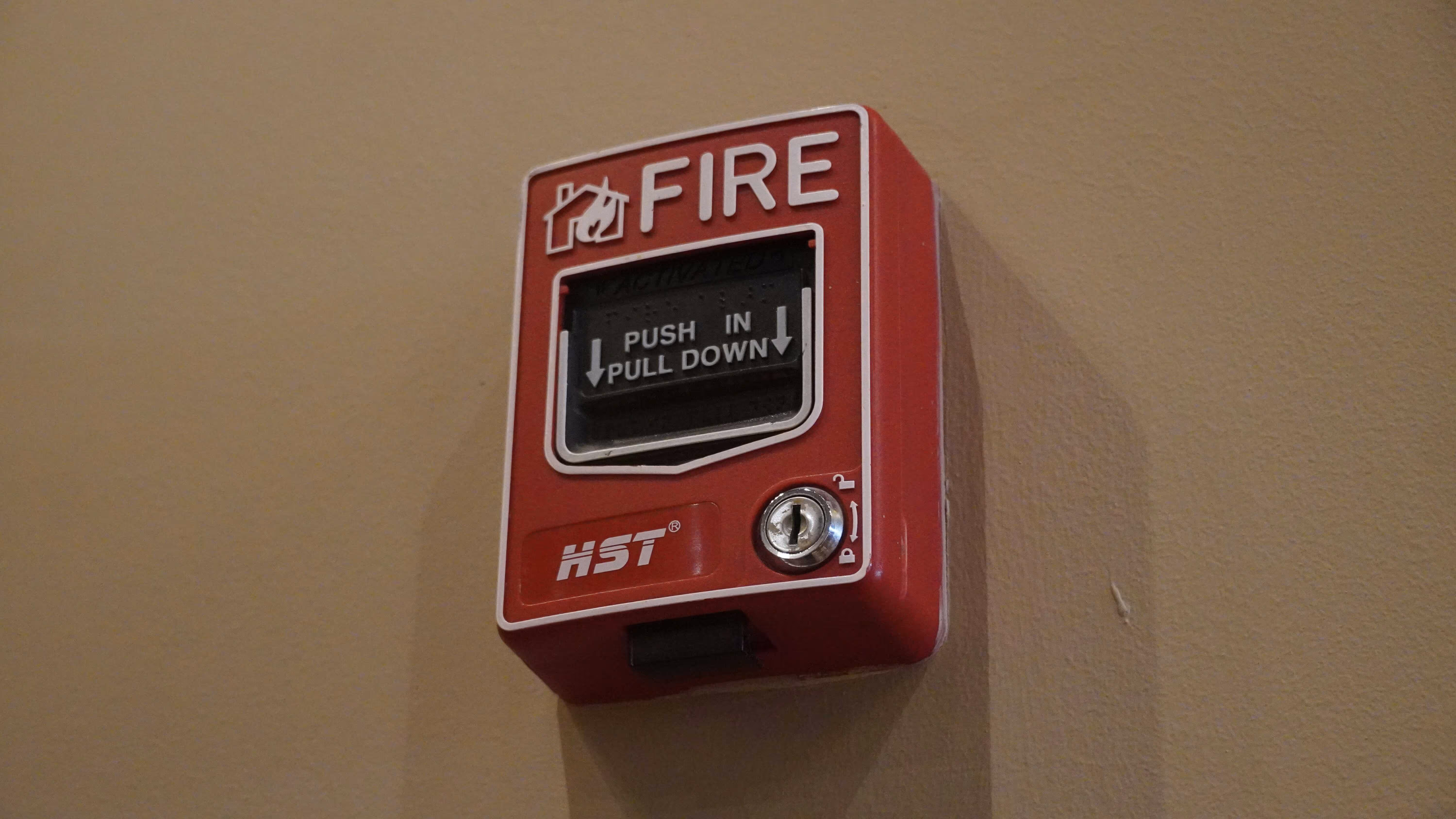 Red wall-mounted fire alarm pull station labeled “Push in, Pull down.”