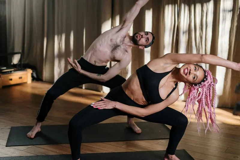 Two people doing a side stretch pose on yoga mats
