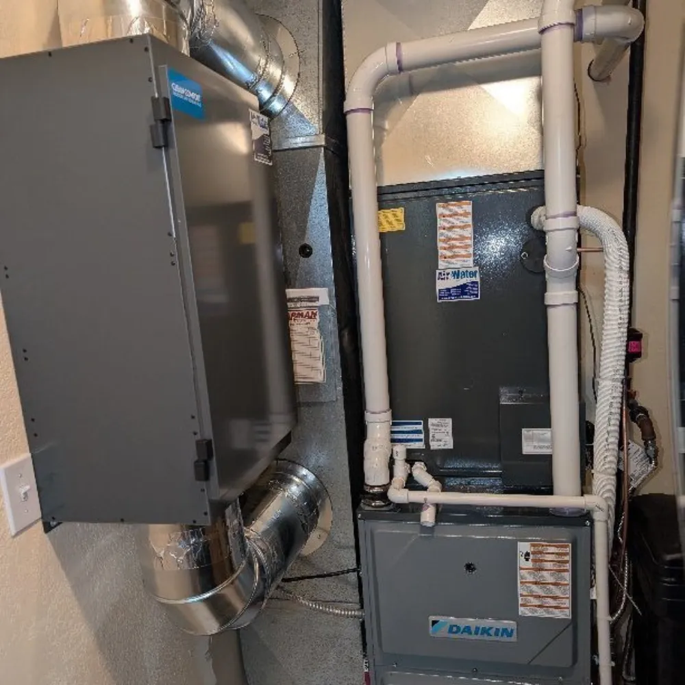 Indoor Daikin furnace and air handling system with connected HVAC ductwork and white PVC pipes.